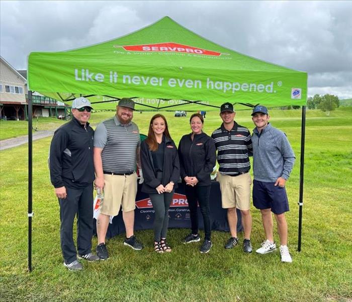 Group of SERVPRO employees under SERVPRO tent at golf outing